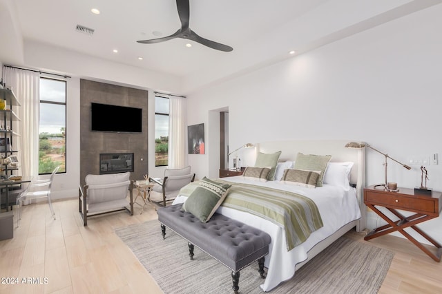 bedroom with light wood-style flooring, recessed lighting, visible vents, and a large fireplace