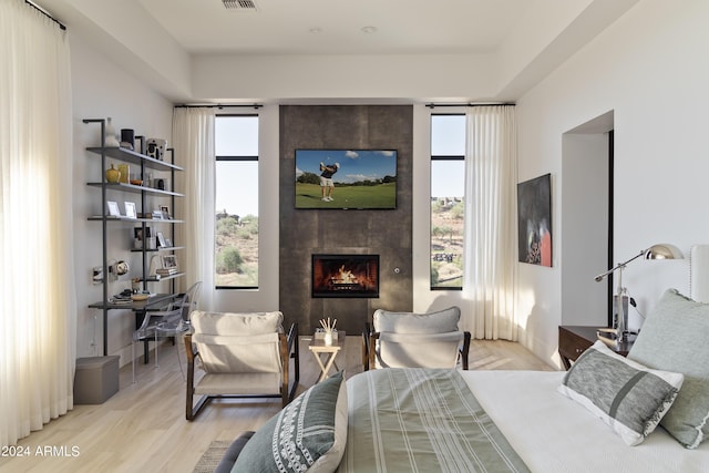 bedroom with multiple windows, a fireplace, visible vents, and light wood finished floors