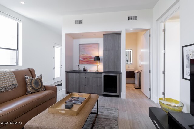 living room featuring wine cooler, light wood-style floors, and visible vents