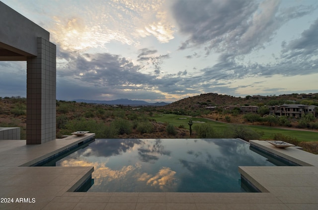 view of pool featuring a mountain view, an infinity pool, and a patio area