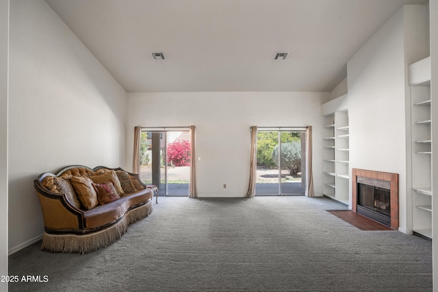 1226 E Greenway Cir, Mesa, AZ 85203 - living room featuring carpet, baseboards, a tile fireplace, built in shelves, and lofted ceiling