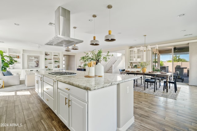 kitchen featuring island exhaust hood, white cabinetry, light hardwood / wood-style floors, pendant lighting, and light stone counters