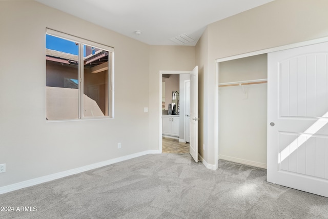 unfurnished bedroom featuring light carpet and a closet