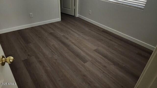 unfurnished bedroom with baseboards and dark wood-style flooring