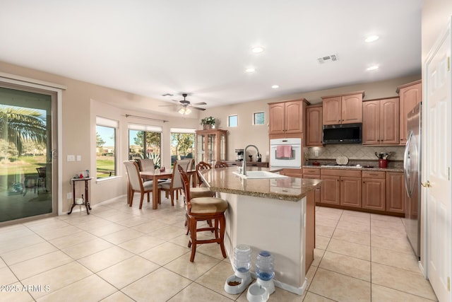kitchen with light tile patterned floors, visible vents, backsplash, appliances with stainless steel finishes, and a sink