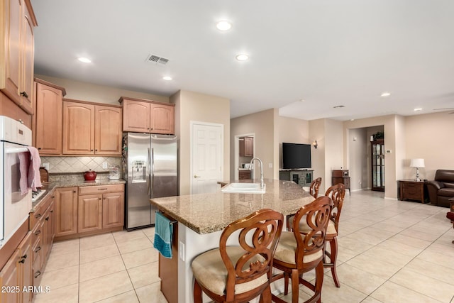 kitchen featuring light tile patterned floors, visible vents, open floor plan, stainless steel refrigerator with ice dispenser, and a sink