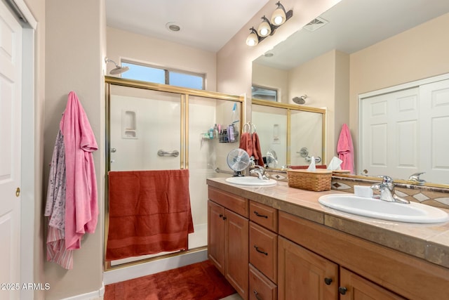 full bathroom with double vanity, a shower stall, visible vents, and a sink
