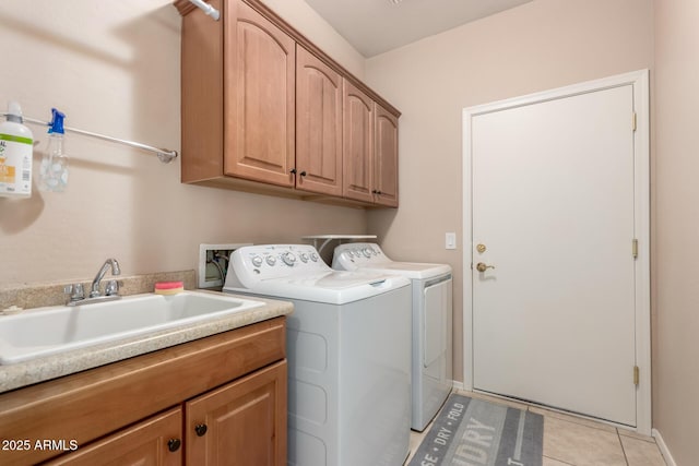 clothes washing area with cabinet space, washing machine and dryer, light tile patterned floors, and a sink