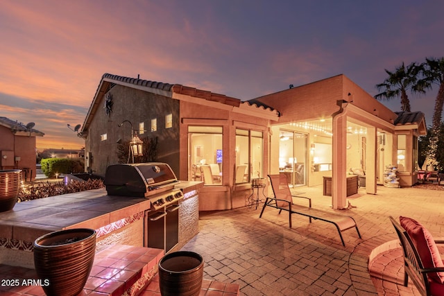 patio terrace at dusk featuring an outdoor kitchen