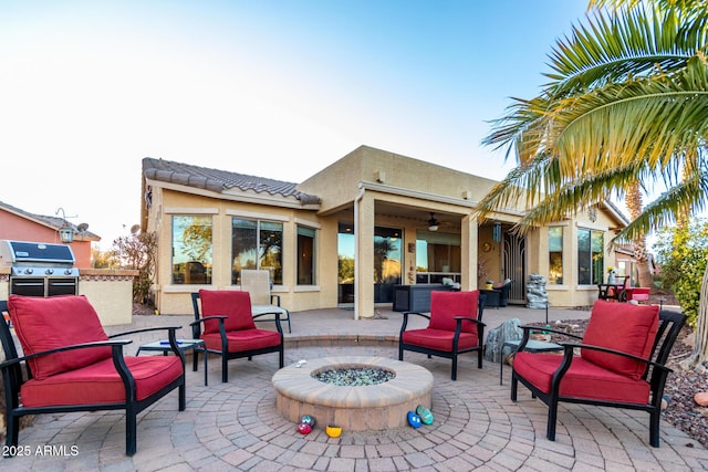 view of patio / terrace featuring an outdoor fire pit, an outdoor kitchen, a ceiling fan, and area for grilling