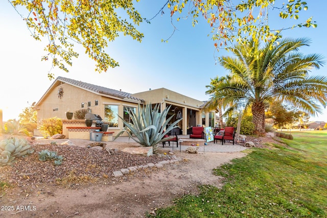 back of property with a patio area, a yard, exterior kitchen, and stucco siding