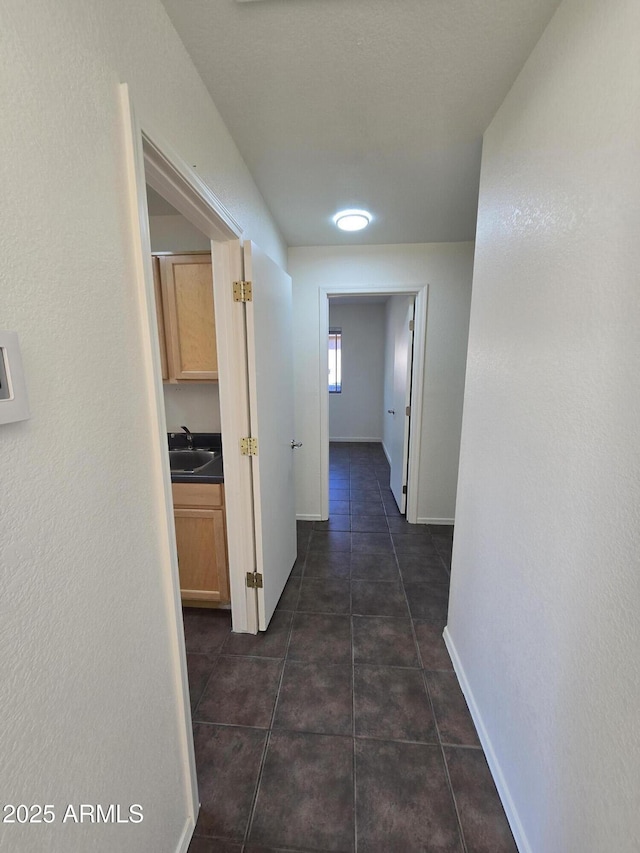 hall with sink and dark tile patterned flooring