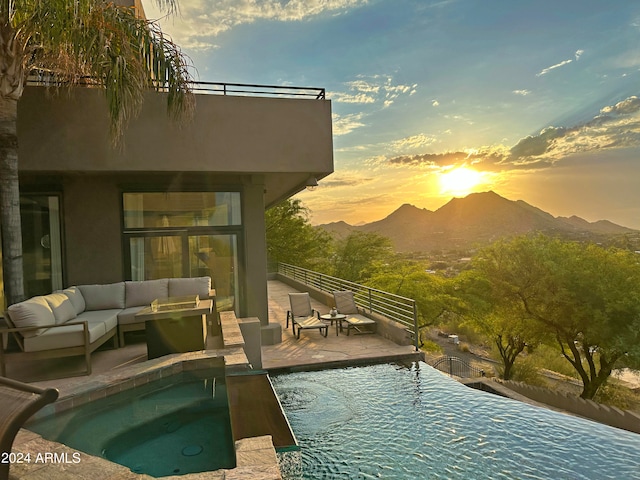 pool at dusk featuring an outdoor living space, a patio area, and a mountain view