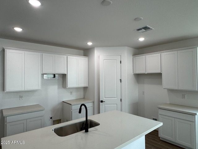 kitchen featuring white cabinetry, sink, and an island with sink