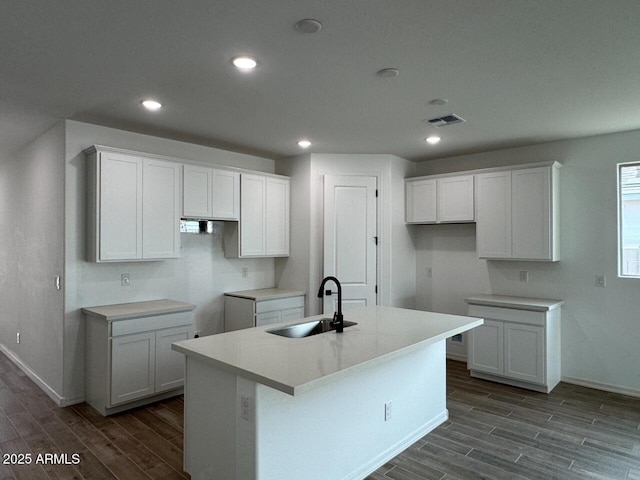 kitchen with white cabinetry, wood-type flooring, sink, and an island with sink