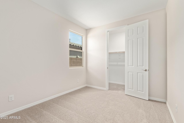 unfurnished bedroom featuring light colored carpet, a spacious closet, and a closet