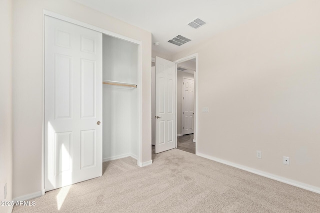 unfurnished bedroom featuring light colored carpet and a closet