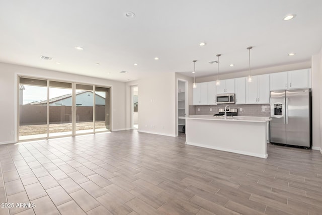 kitchen with sink, hanging light fixtures, appliances with stainless steel finishes, decorative backsplash, and white cabinets