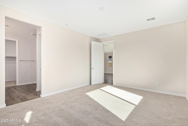 unfurnished bedroom featuring carpet flooring, a spacious closet, and a closet