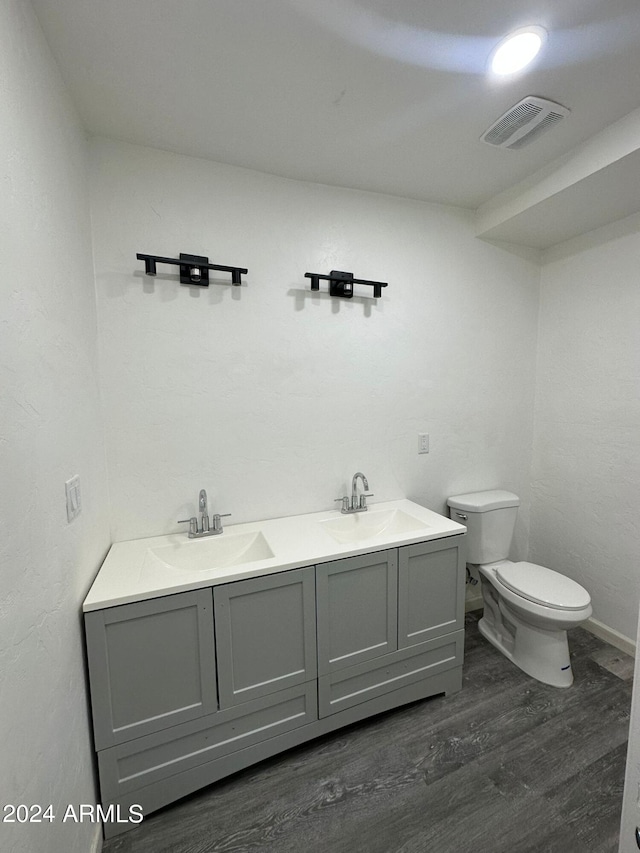 bathroom with dual vanity, hardwood / wood-style flooring, and toilet