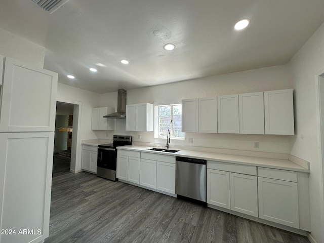 kitchen featuring white cabinetry, hardwood / wood-style floors, wall chimney exhaust hood, sink, and appliances with stainless steel finishes