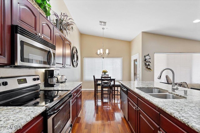 kitchen with sink, stainless steel appliances, a chandelier, vaulted ceiling, and decorative light fixtures