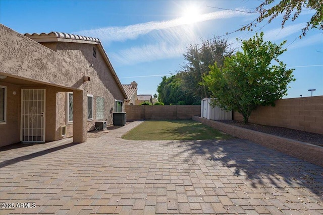 view of patio with central AC unit and a storage shed