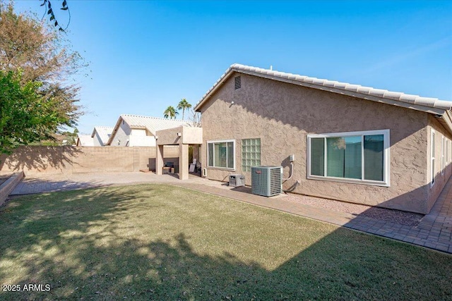 rear view of house featuring cooling unit, a patio area, and a yard