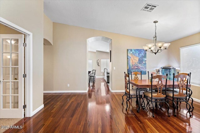 dining room featuring lofted ceiling, dark hardwood / wood-style floors, and an inviting chandelier