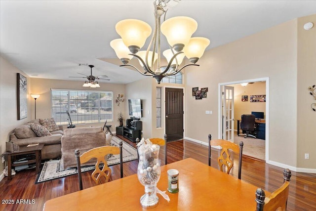 dining area featuring dark hardwood / wood-style flooring and ceiling fan with notable chandelier