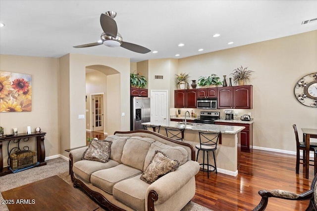 living room with dark hardwood / wood-style flooring, ceiling fan, and sink