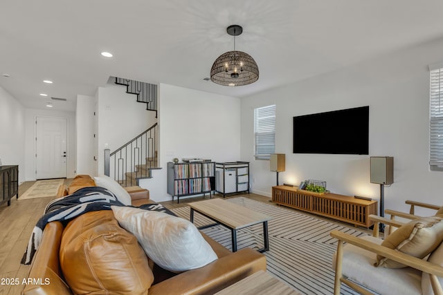 living room featuring baseboards, stairs, light wood-style floors, a chandelier, and recessed lighting