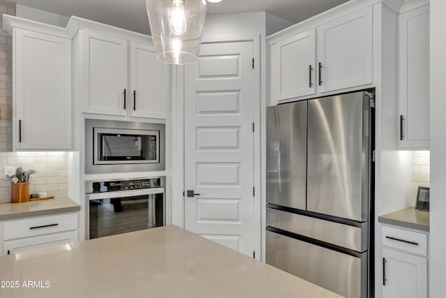 kitchen featuring stainless steel appliances, tasteful backsplash, light countertops, and white cabinetry