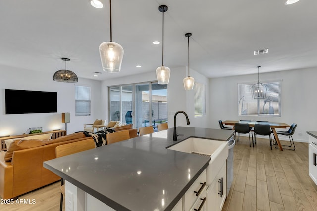 kitchen with dark countertops, visible vents, a sink, and light wood-style flooring