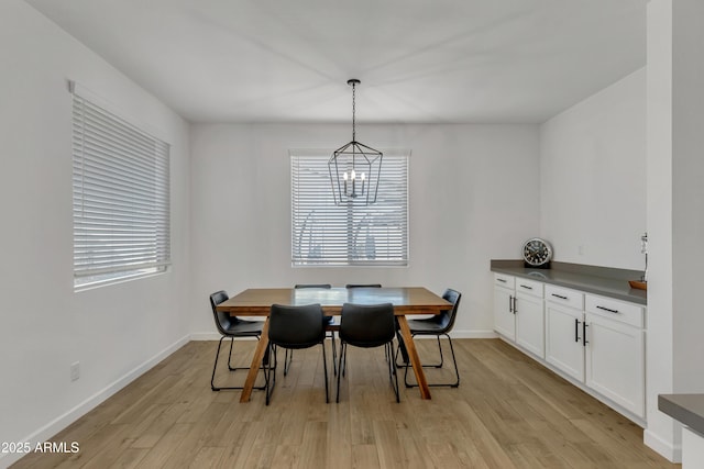 dining room with baseboards, a notable chandelier, and light wood-style floors