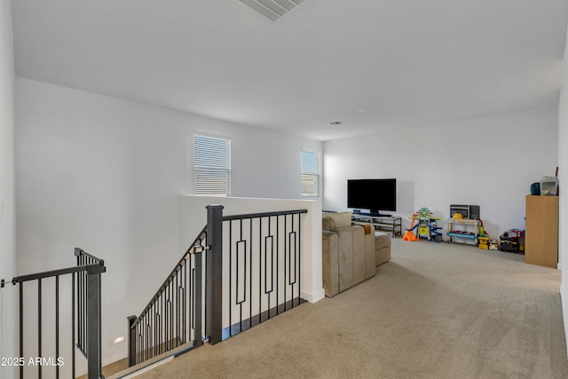 hall featuring visible vents, carpet flooring, and an upstairs landing