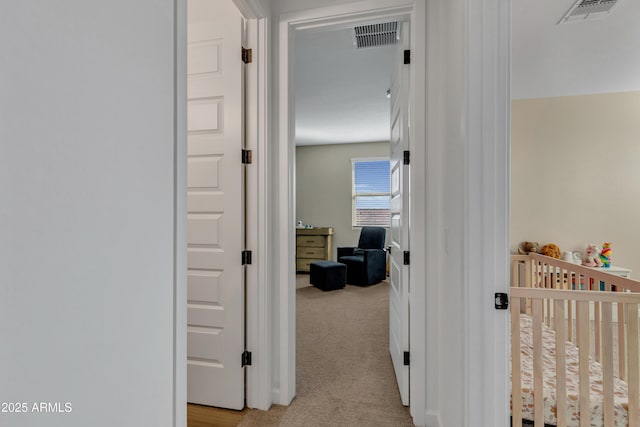 hallway featuring light carpet and visible vents