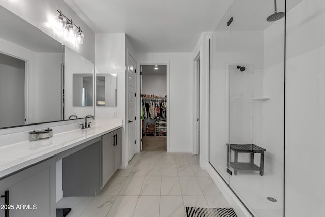 full bath featuring marble finish floor, a stall shower, a walk in closet, and vanity