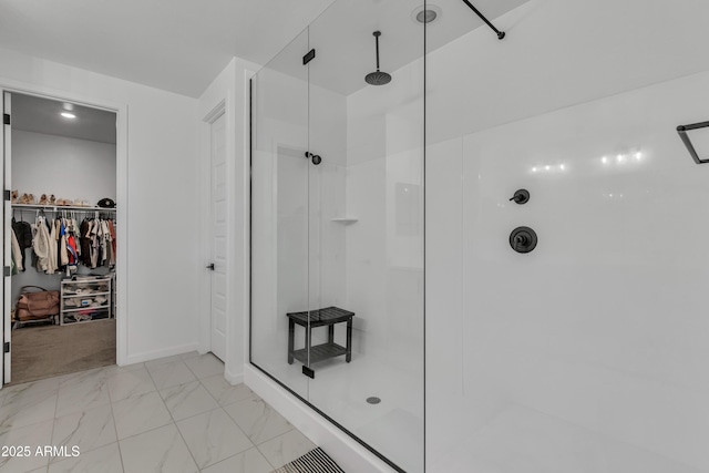 bathroom with a stall shower, marble finish floor, a walk in closet, and baseboards