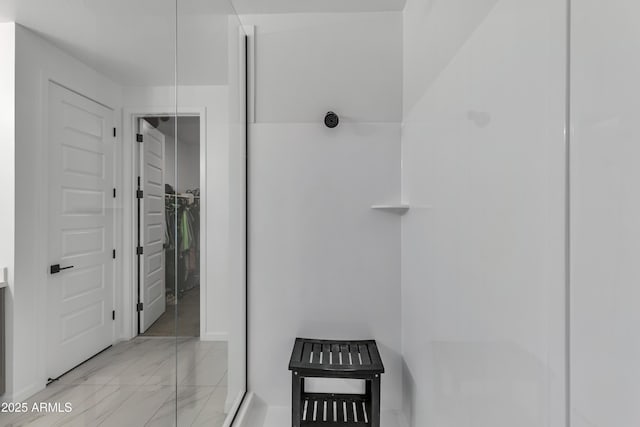 bathroom with marble finish floor and a spacious closet