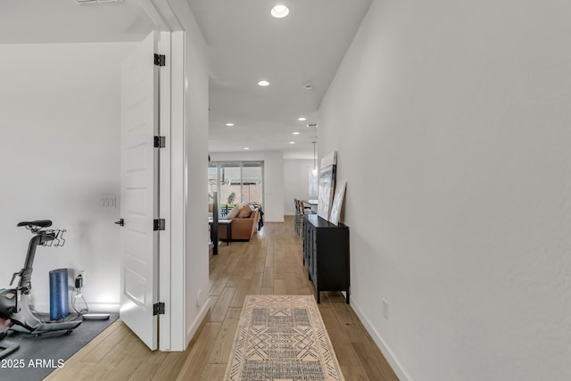 hallway with light wood-style flooring, visible vents, baseboards, and recessed lighting