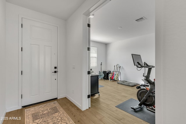 foyer featuring baseboards, visible vents, and wood finished floors