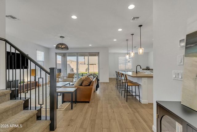 living area featuring recessed lighting, visible vents, stairway, and light wood finished floors