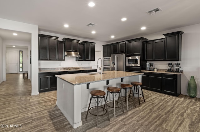 kitchen with a breakfast bar, a kitchen island with sink, sink, light hardwood / wood-style floors, and stainless steel appliances