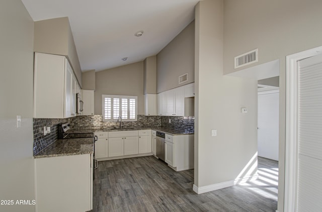 kitchen with sink, appliances with stainless steel finishes, white cabinetry, backsplash, and hardwood / wood-style floors