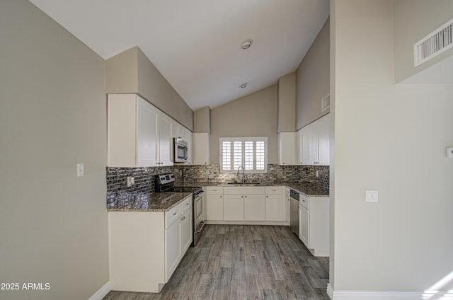 kitchen featuring appliances with stainless steel finishes, sink, dark stone counters, and white cabinets