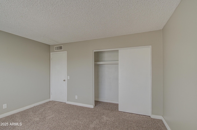 unfurnished bedroom featuring light colored carpet, a closet, and a textured ceiling