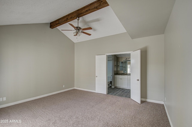 unfurnished bedroom with connected bathroom, vaulted ceiling with beams, ceiling fan, and carpet flooring