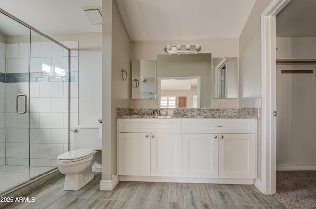 bathroom with hardwood / wood-style flooring, vanity, toilet, and walk in shower