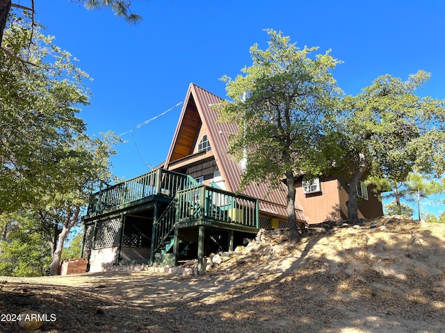 rear view of house with a deck, stairs, and metal roof